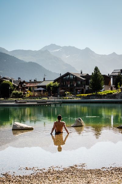 Une personne est assise dans l'eau au bord du lac