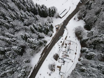 Vue drone du gîte et auberge de Carri à La Chapelle en Vercors, avec la route enneigée qui serpente à travers une forêt [...]