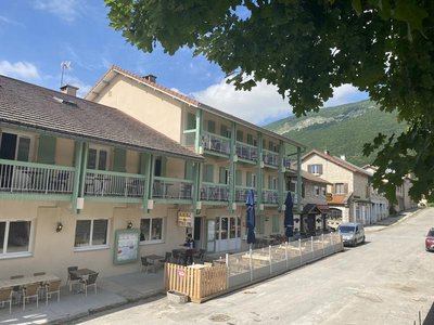Façade avec hôtel et terrasses aux étages. Restaurant au rez-de-chaussée avec deux terrasses, parasols bleus fermés, [...]