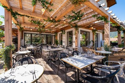 terrasse avec tables dressées sous pergolas en bois et végétaux