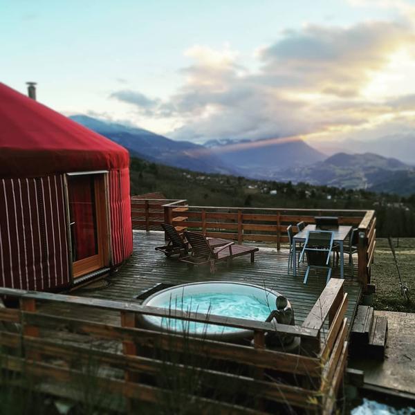 Une yourte rouge avec une vue dégagée sur les montagnes. Sur la terrasse, deux chaises longues en bois et une table pour [...]