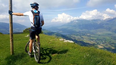 Sportif au sommet d'un sentier VTT et vue sur le plateau matheysin